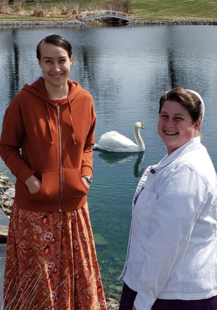 Two women by the pond with a swan on the property
